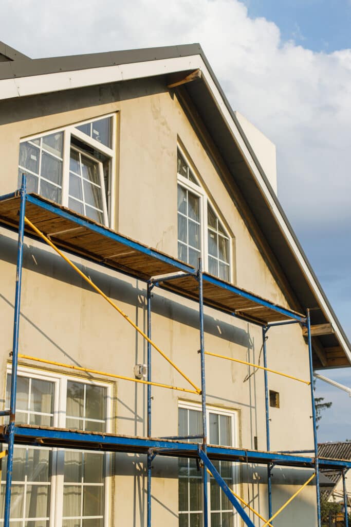 House insulation concept. Facade insulation with mineral wool, thermal improvement and energy saving. Modern farmhouse renovation, scaffolding platform and stone wool covered with plaster